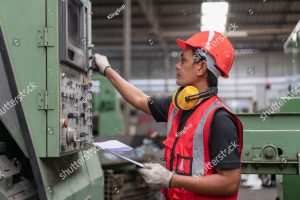 stock photo asian male engineer in red safety vest and helmet checking and repairing old cnc machinery at 2121316187 1
