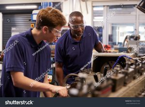 stock photo engineer showing teenage apprentice how to use lathe 760415905