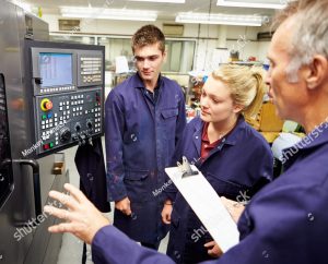 stock photo engineer teaching apprentices to use computerized lathe 165333119 1
