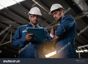 stock photo factory technicians are discussing or planning work they wear uniforms safety helmets and 1660979758