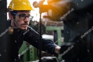 stock photo factory technicians work on the front of the machine he wears a uniform helmet and protective 1662130582